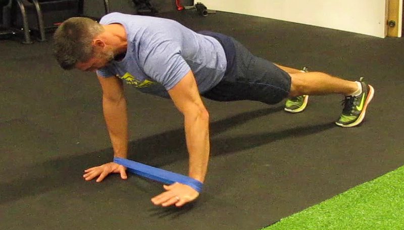 Performing banded hand taps in plank position